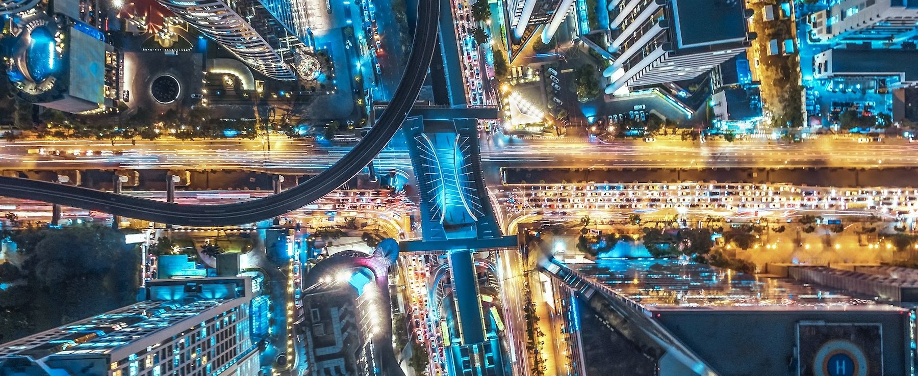Letecký pohled na noční město osvětlené mnoha světly symbolizujícími energetickou účinnost ve městech v kontextu inteligentního řízení spotřeby energie společnosti CANCOM.